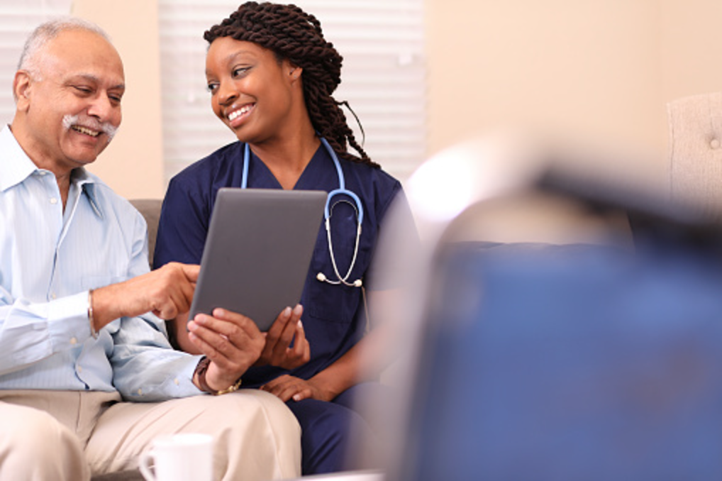 Nurse and an older man reviewing daily health readings on a tablet