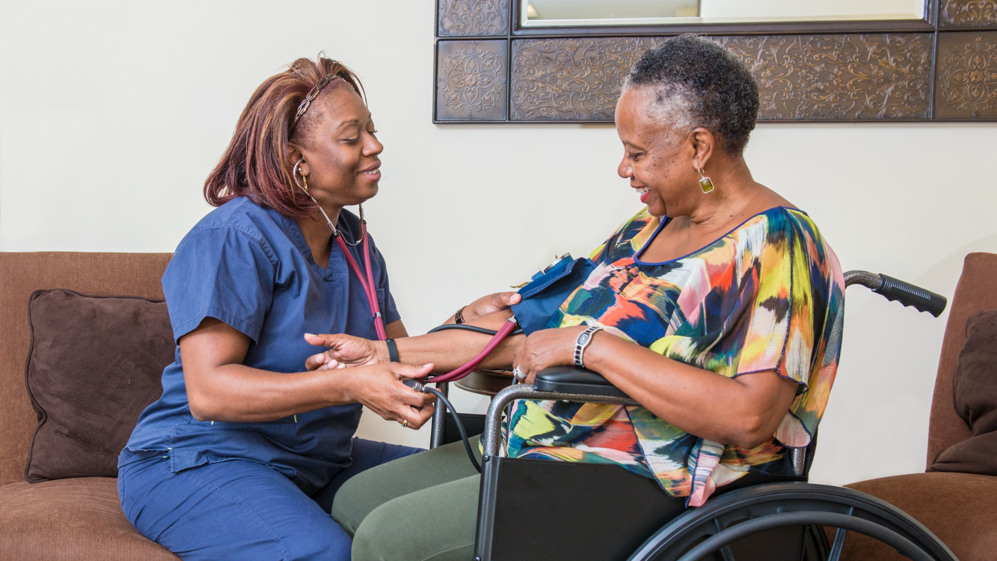 Home health nurse checking an older woman's blood pressure in her living room